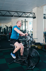 Fototapeta na wymiar Powerful man trains with air bike. Functional training concept