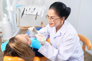 Dentist examining teeth of female patient