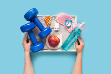 Biohacking health treatment with sports, healthy nutrition, sleep and vitamins. Woman's hands hold a tray with a set for biohacking on a blue background flat view