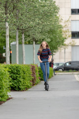 Junge Frau fährt mit e-Scooter in der Stadt