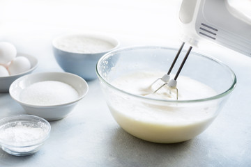 Mixer whipping eggs in a glass bowl 