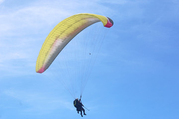 Tandem paraglider flying yellow wing