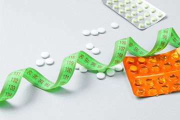Diet pills. Ruler and pills on a gray background. Weight loss concept