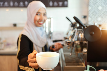 young muslim barista girl hands showing a cup of coffee