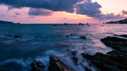 Obraz premium Long exposure image of Dramatic sky and wave seascape with rock in sunset scenery background