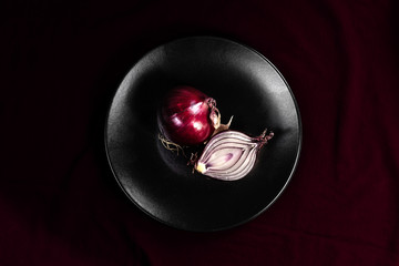 red onions on black plate and purple background