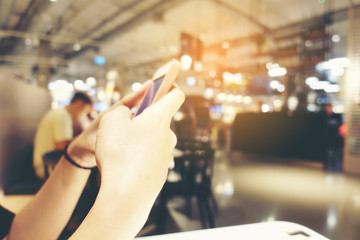 Close up of women's hands with a pink nails holding cell telephone, hipster girl watching video and texting a message to her family on mobile phone during coffee break in restaurants