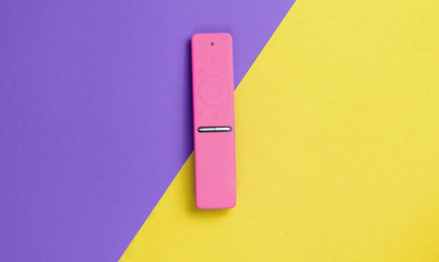 TV remote control in pink silicone case on colored paper background. Minimalism, top view