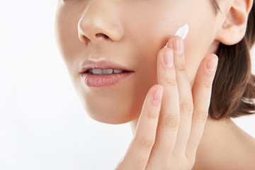 Obraz na płótnie Canvas Close up of female applying cream on face