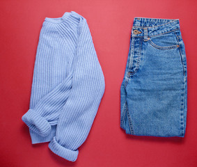 Women's jeans and sweater on red background. Top view. Minimalism
