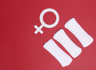 Menstruation days concept. Female gender symbol, pads on red background. Woman's hygiene. Top view