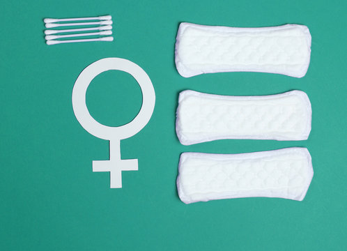 Products for feminine hygiene, self-care and health, female gender symbol on mint color background. Ear sticks, pads. Top view