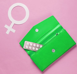 Women Health. Female gender symbol, pills in green purse on  pink background.