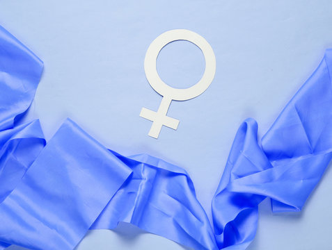 Female gender symbol, silk ribbon on pastel blue background. Minimalism. Top view
