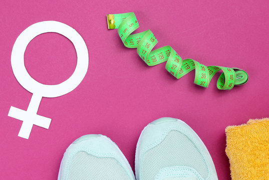 Female sport, weight loss. Training concept. Sport shoes, towel, ruller, Gender symbol feminism on a purple background. Top view