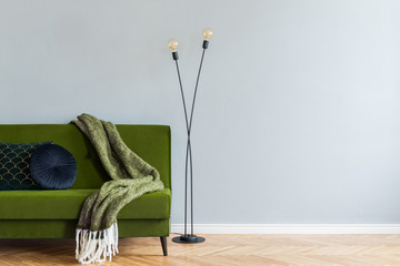 Minimalistic home interior with green velvet design sofa, black lamp, elegant blanket and pillows....