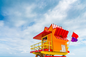 Orange and red lifeguard tower under a cloudy sky in Miami Beach