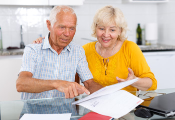 Mature family couple with documents at kitchen table