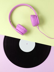 Retro 70s. Music lover. Headphones, lp record on green pink background. Flat lay. Top view.