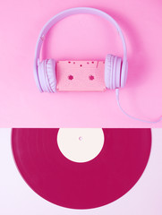 Minimalism. Retro style. Headset with audio cassette, lp record on pink gray background. Creative...