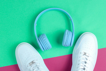 Minimalism. Music lover.  Headphones, white sneakers on purple mint background. Top view. Flat lay