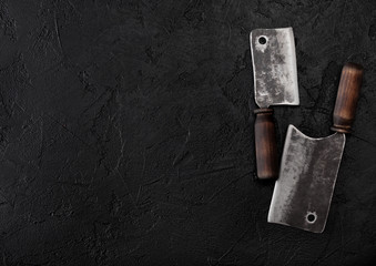 Vintage meat knife hatchets on black stone table background. Butcher utensils. Space for your text