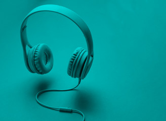 3D surround photo modern blue headphones with cable on green background.