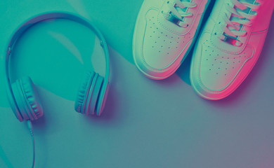 Sneakers with wireless headphones. Retro wave, neon light, ultraviolet. Top view, minimalism