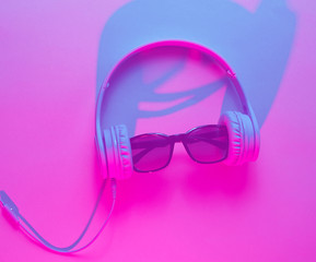 Sunglasses with headphones. Retro wave, blue pink neon light, duotone effect. Top view, minimalism