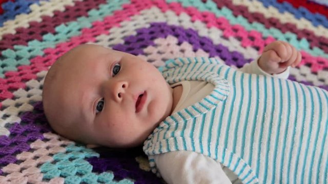 Baby on a knitted colored blanket,a beautiful baby can not fall asleep on a knitted veil, teething pain in infants