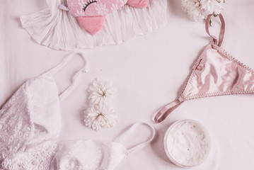 Flat lay for fashion blog and social media. Woman's glamour white and beige beauty accessories on a white background. Lingerie, jewelry, perfumes, cream, soap, panties, sleep mask, spiral hair ties. 