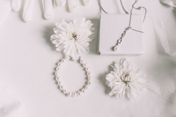 White bridal accessories for wedding background with pearls, white satin ribbons and lace, gloves, bracelet,flat lay for fashion blog, top view