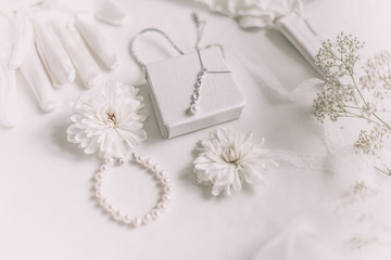 Obraz na płótnie Canvas White bridal accessories for wedding background with pearls, white satin ribbons and lace, gloves, bracelet,flat lay for fashion blog, top view