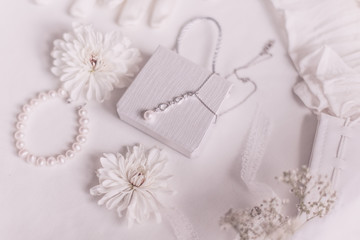 Obraz na płótnie Canvas White bridal accessories for wedding background with pearls, white satin ribbons and lace, gloves, bracelet,flat lay for fashion blog, top view