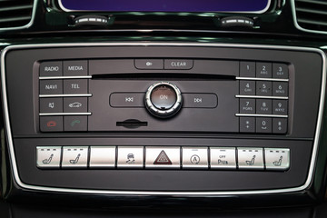 The central control console on the panel inside the car close-up with climate control and audio system and a hole for the CD and emergency button in gray and black. Auto service industry. Comfort.