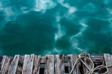 Old wooden pier near the blue sea with nautical ropes and text space.