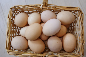 Chicken eggs in a basket on a wooden floor. Close-up