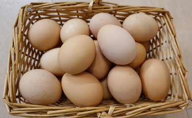 Chicken eggs in a basket on a wooden floor. Close-up