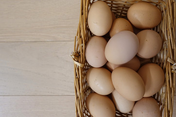 Chicken eggs in a basket on a wooden floor. Close-up