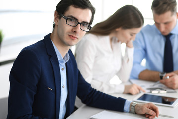 Group of business people discussing questions at meeting in modern office. Headshot of businessman at negotiation. Teamwork, partnership and business concept