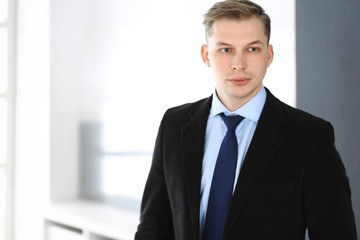 Headshot of businessman standing straight in office. Success and business workplace concept