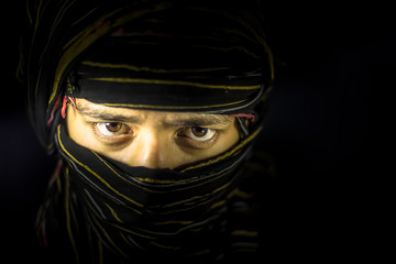Striking portrait of male teenager isolated on black with piercing expressive eyes along with a...