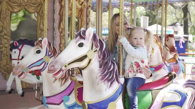 A woman and a child riding a horse on a carousel.