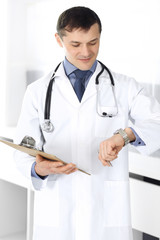 Doctor man using clipboard for filling up medication history records. Perfect medical service in clinic. Physician at work in hospital. Medicine and healthcare concepts