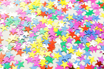 Multicolored stars of confetti on a white background, view from above