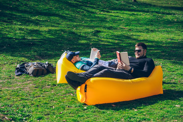two men friends laying on yellow inflatable mattress reading books