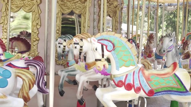 Horses on the carousel ride in a circle, slow motion. Attraction, amusement Park.