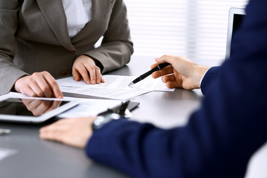 Business People And Lawyer Discussing Contract Papers Sitting At The Table, Hands Close-up. Teamwork Or Group Operations Concept