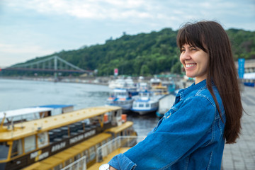 young pretty woman looking on river at morning time. boats in dock