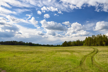 clouds over green meadow and country road